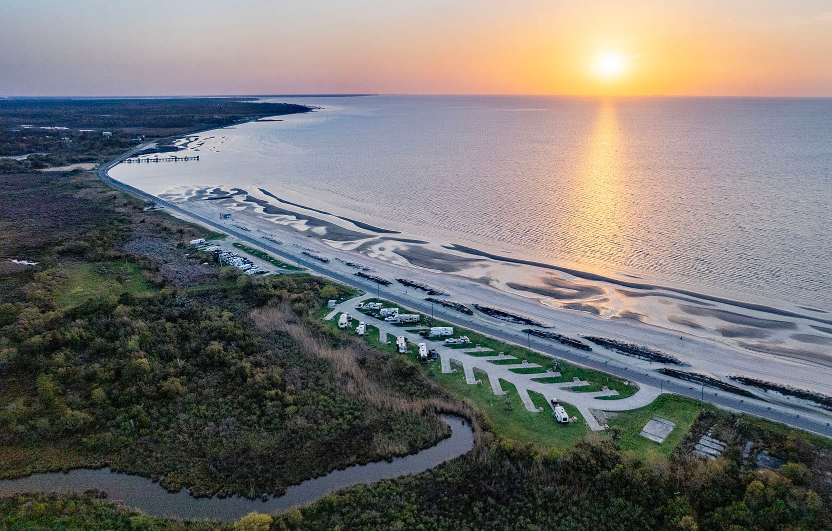 Aerial view of Bay St. Louis Beachfront RV Park at sunset, RV pads lining the beach along South Beach Boulevard